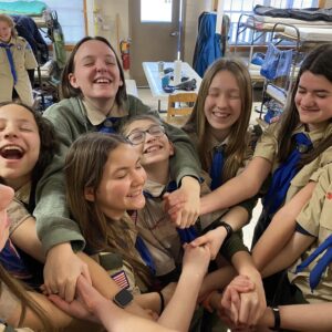 girls in scout uniform reaching into the center of a circle