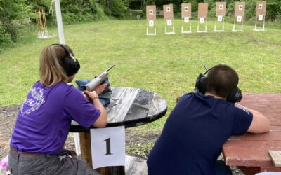 A male and female Scout aim their rifles at targets on the shooting range