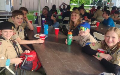 Five youth members and two adult members of Troop 122 relax at the lunch table